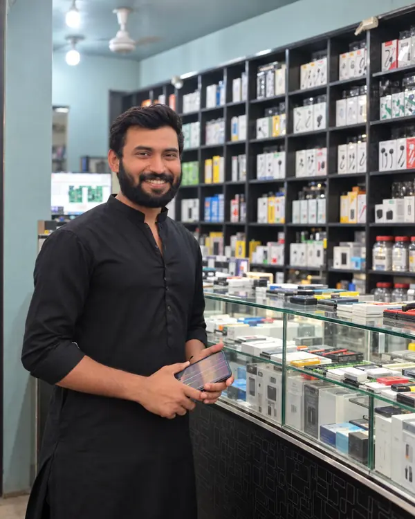 Sikandar, owner of SK Mobiles, at the shop counter